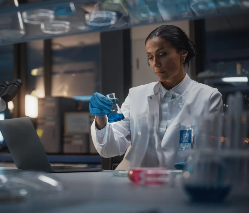 A woman in a lab coat diligently working on a project in a laboratory setting.